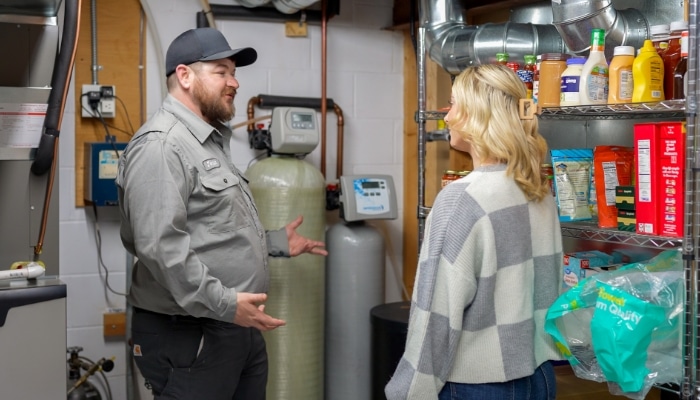 Zoomed Out Plumber Explaining Water Filtration System To Customer